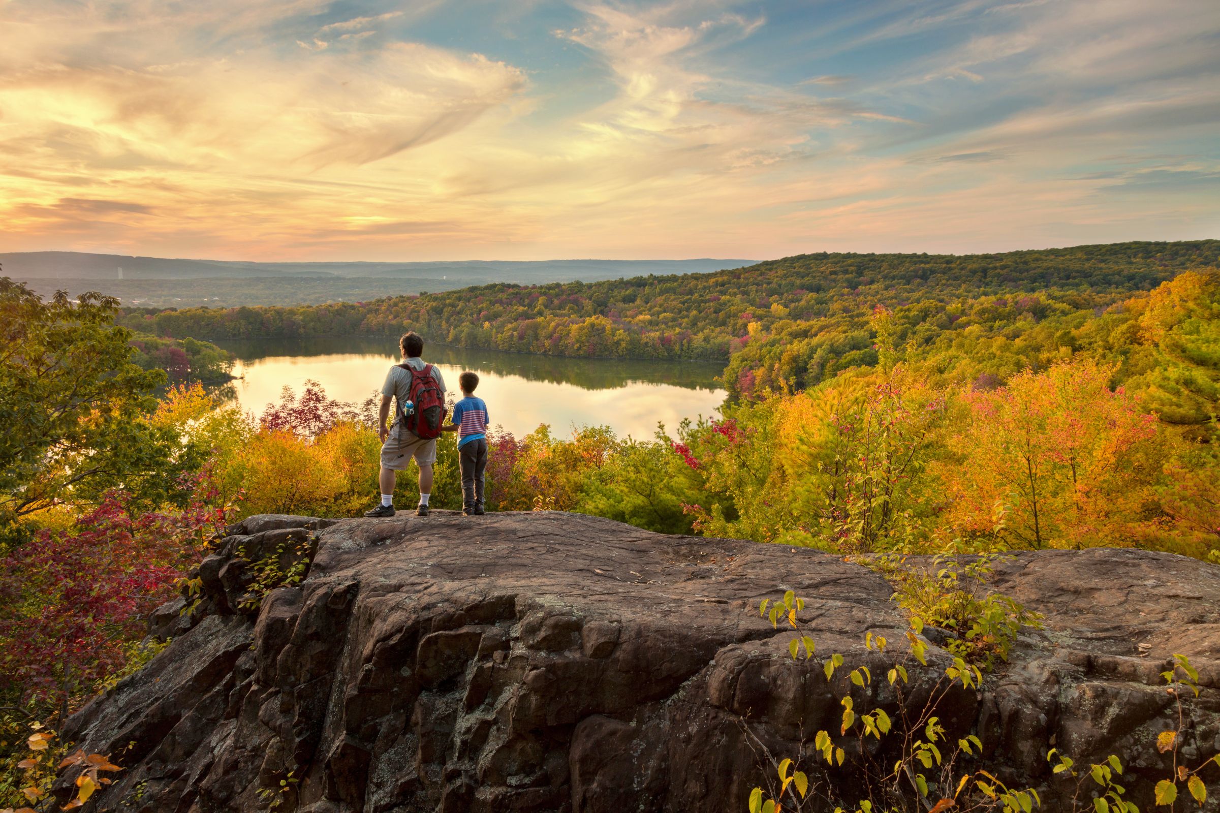 parent and child looking out over hills and lake